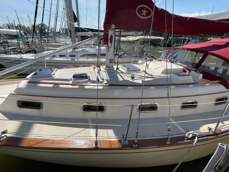 Slide: The Image of 1992 Island Packet 32 sailboat with red sail cover, docked in marina. - 5