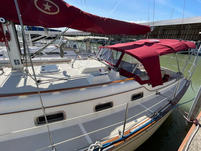Slide: The Image of 1992 Island Packet 32 sailboat with red canopy docked in marina. - 6