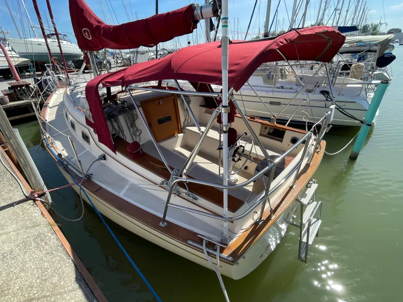 Slide: The Image of 1992 Island Packet 32 sailboat docked, featuring maroon canopy and wooden accents. - 7
