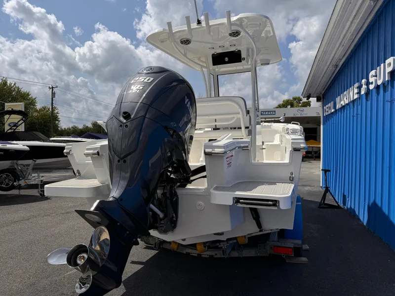 Slide: The Image of 2025 Parker 2200 Center Console boat with powerful outboard motor, parked near blue building. - 5