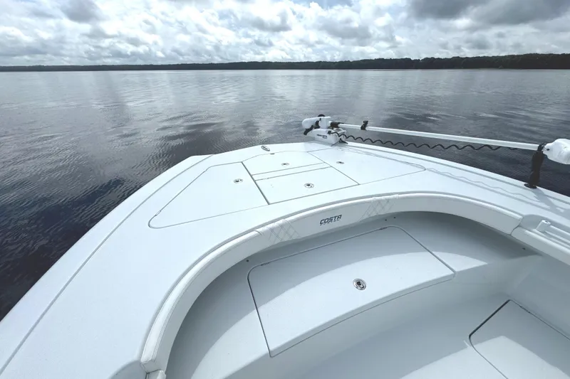 Slide: The Image of 2020 Costa Custom Boats 264 HC on calm water under cloudy sky. - 12