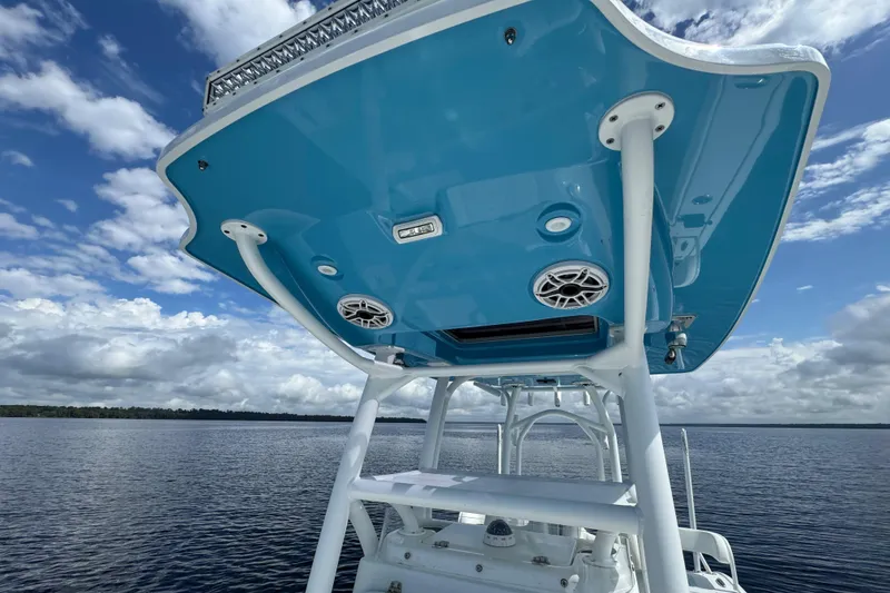 Slide: The Image of 2020 Costa Custom Boats 264 HC, blue canopy, speakers, on calm water under cloudy sky. - 15