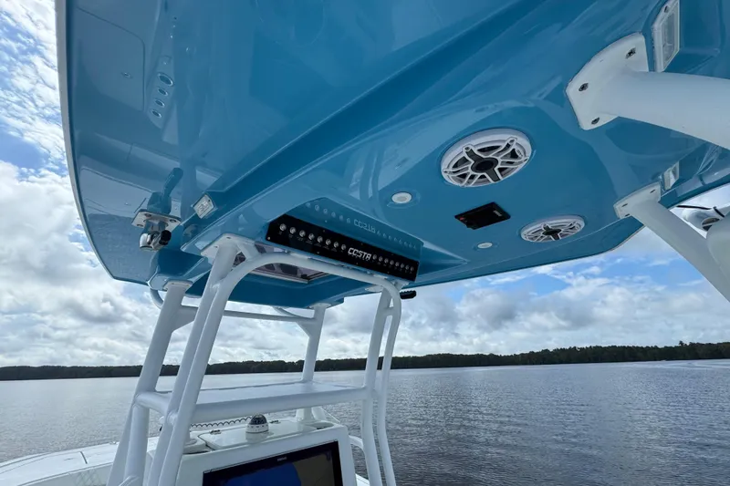 Slide: The Image of 2020 Costa Custom Boats 264 HC with blue canopy and speakers on a calm lake. - 18