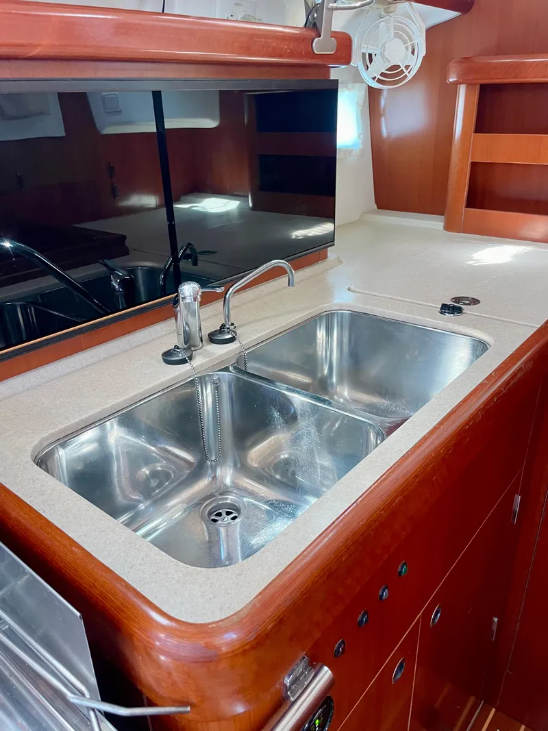 Slide: The Image of Beneteau 423 (2007) yacht kitchen with dual stainless steel sink and wooden cabinetry. - 47