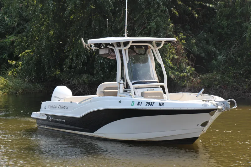 The Image of 2022 Finseeker 230 CC boat on calm water, surrounded by lush greenery. - 0