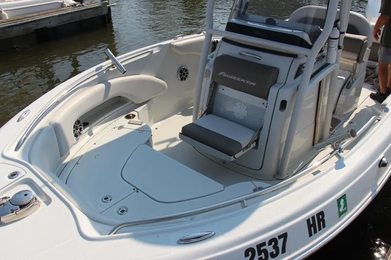 Slide: The Image of 2022 Finseeker 230 CC boat interior with seating and console, docked on water. - 13
