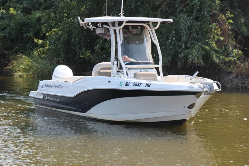 Slide: The Image of 2022 Finseeker 230 CC boat on calm water, surrounded by lush greenery. - 20