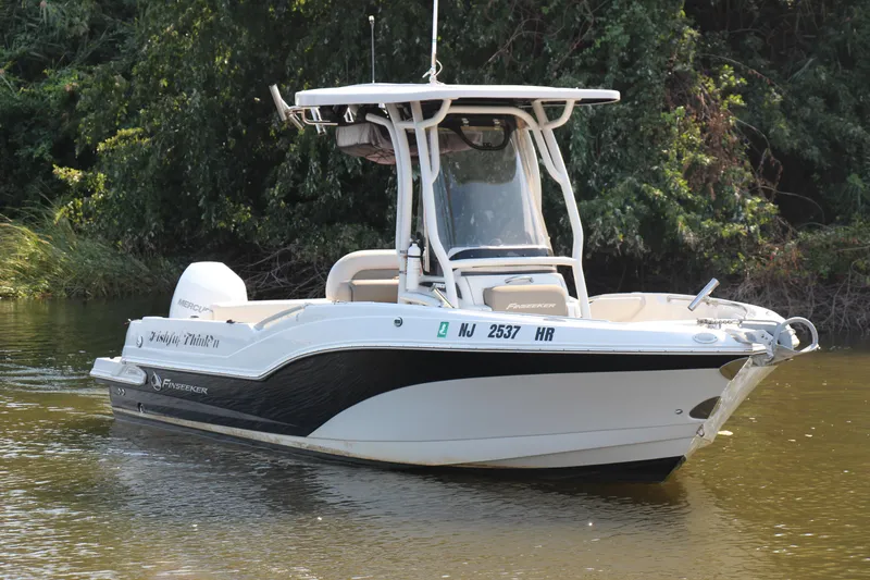 Slide: The Image of 2022 Finseeker 230 CC boat on calm water, surrounded by lush greenery. - 21