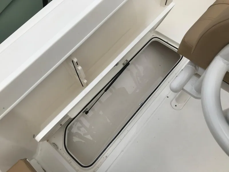 Slide: The Image of 2024 Bayliner Trophy T24CC storage compartment with open hatch and steering wheel. - 13