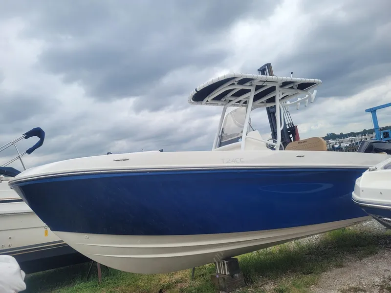 Slide: The Image of 2024 Bayliner Trophy T24CC boat with blue hull, parked outdoors under cloudy skies. - 2