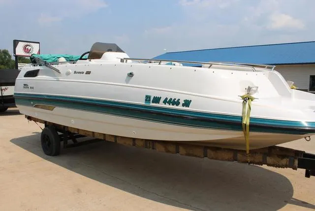 Slide: The Image of 1994 Chaparral 220 Sunesta Deck boat on trailer, white with teal accents. - 7