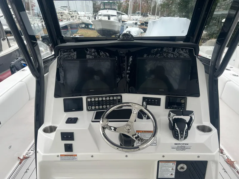 Slide: The Image of 2025 Sea Fox 328 Commander boat dashboard with steering wheel and controls. - 2