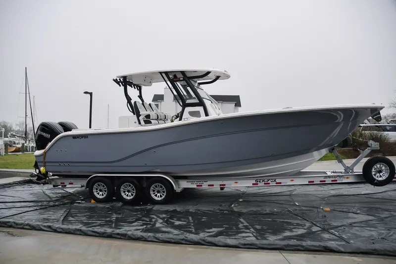 The Image of 2025 Sea Fox 328 Commander boat on trailer, side view, gray hull, parked outdoors. - 0