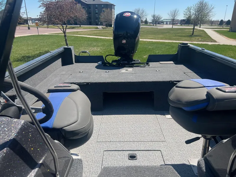 Slide: The Image of 2024 Ranger VS1882SC Angler boat interior with seating and motor, parked on grass. - 6