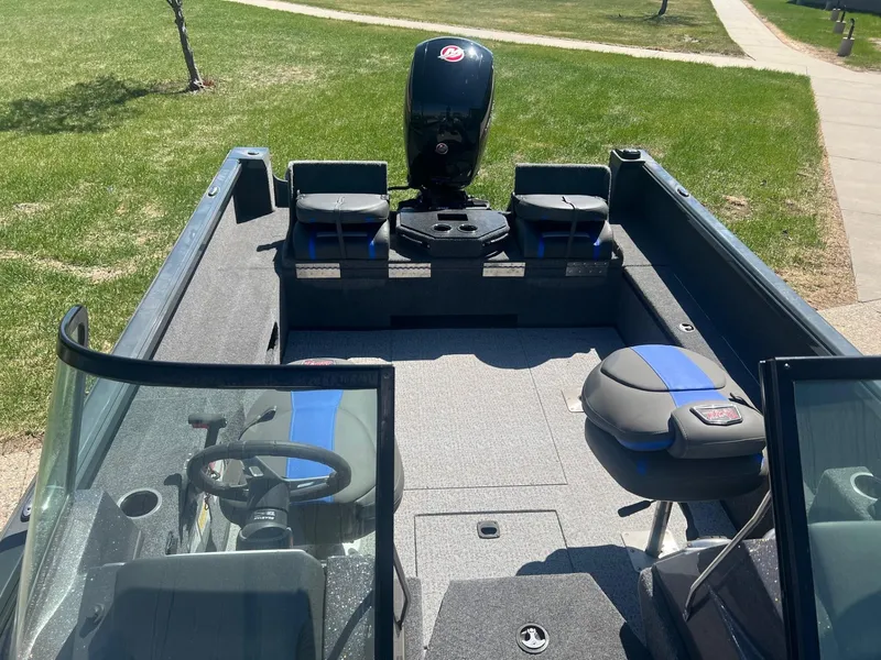 Slide: The Image of 2024 Ranger VS1882SC Angler boat interior with seating and motor, parked on grass. - 7