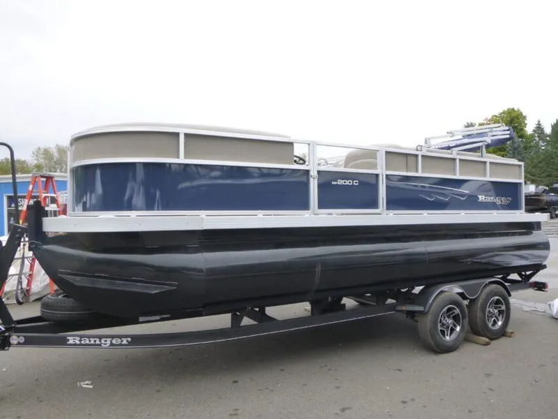 Slide: The Image of 2024 Ranger Reata 200C pontoon boat on trailer, blue and white design. - 0