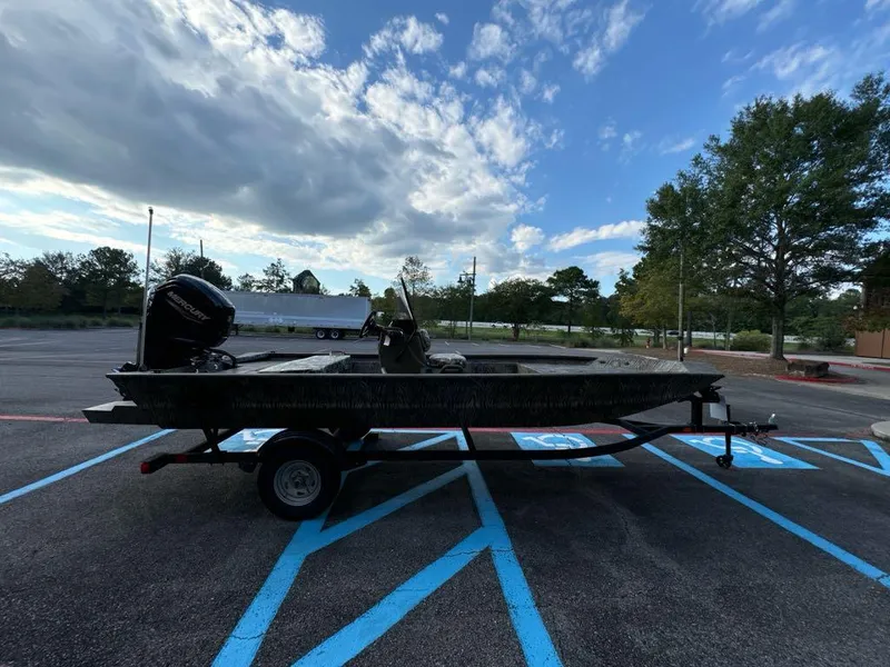 Slide: The Image of 2025 Tracker Grizzly 1860 CC boat on trailer in parking lot under cloudy sky. - 2