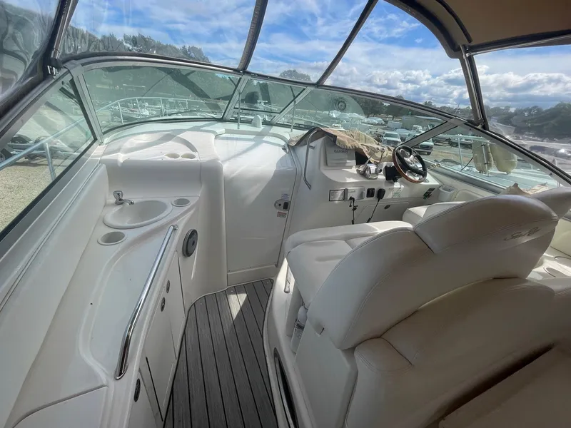 Slide: The Image of 2002 Sea Ray 340 Sundancer cockpit with white seating and steering wheel under clear skies. - 19