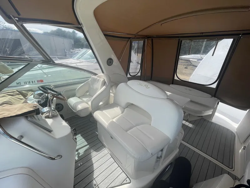 Slide: The Image of 2002 Sea Ray 340 Sundancer interior with white seating and helm, enclosed by tan canopy. - 23