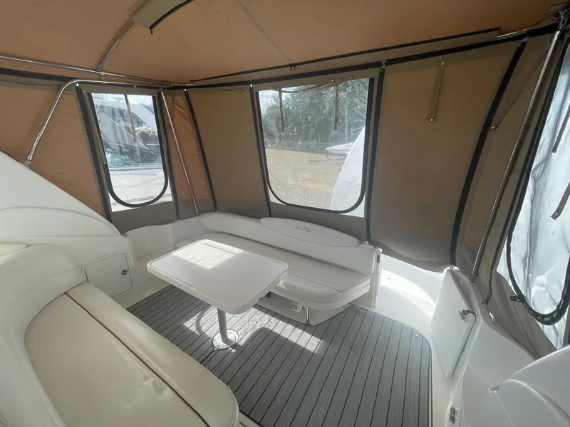 Slide: The Image of 2002 Sea Ray 340 Sundancer interior with seating and table, enclosed by tan canopy. - 25