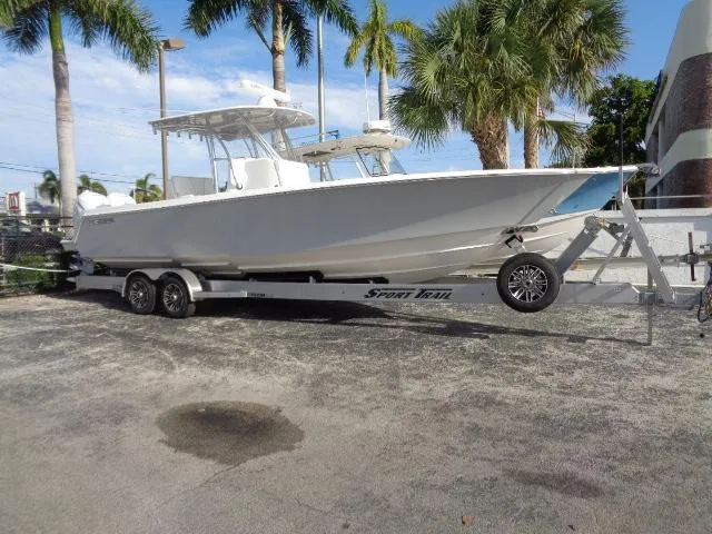 The Image of 2022 Contender 32 ST boat on trailer, parked outdoors with palm trees in the background. - 1