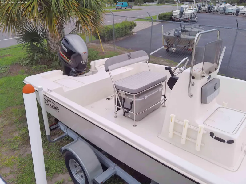 Slide: The Image of 2024 Carolina Skiff EV198 boat on trailer, parked near palm tree. - 4