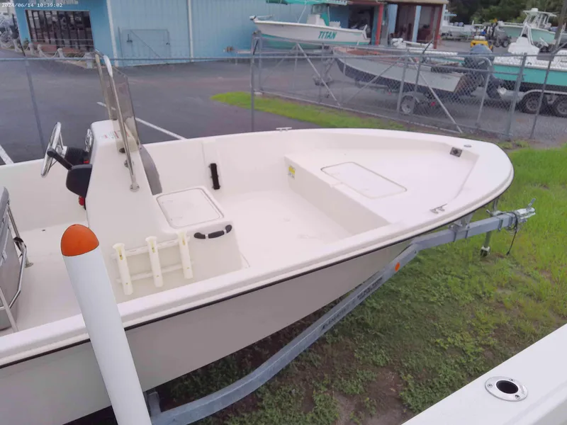 Slide: The Image of 2024 Carolina Skiff EV198 boat on trailer, parked outdoors near a fence. - 5