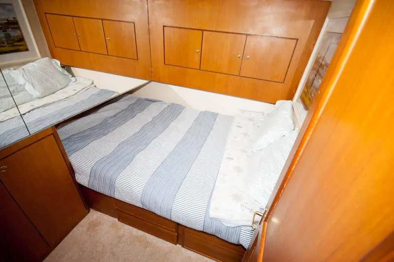 Slide: The Image of Bedroom interior of 1997 Ocean Yachts 53 Super Sport with striped bedding and wooden cabinets. - 10