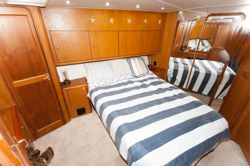 Slide: The Image of Bedroom interior of 1997 Ocean Yachts 53 Super Sport with striped bedding and wooden cabinetry. - 8