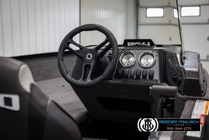 Slide: The Image of 2025 Lund Adventure SS boat dashboard with steering wheel and gauges in a showroom. - 18