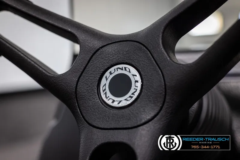 Slide: The Image of Steering wheel of 2025 Lund Adventure SS boat, featuring logo and textured grip. - 20
