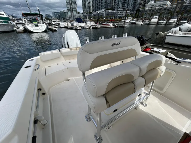 Slide: The Image of 2021 Bulls Bay 230 Center Console boat interior at marina, featuring seating and water view. - 13