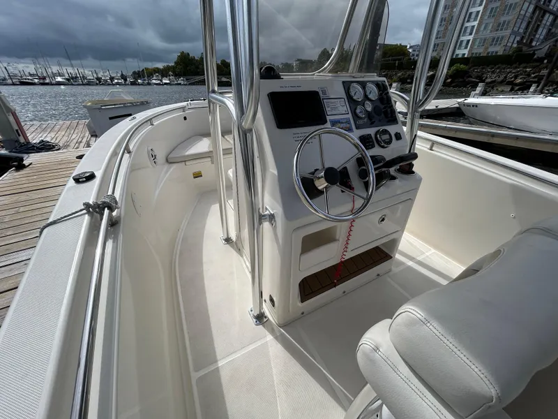 Slide: The Image of 2021 Bulls Bay 230 Center Console boat interior with steering wheel and controls, docked by the water. - 16