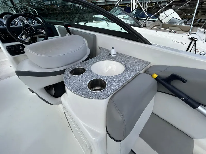 Slide: The Image of 2021 NauticStar 243 DC boat interior with helm, sink, and cup holders. - 11