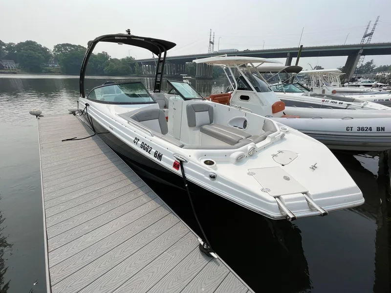 Slide: The Image of 2021 NauticStar 243 DC boat docked at marina, sleek design, calm water backdrop. - 2