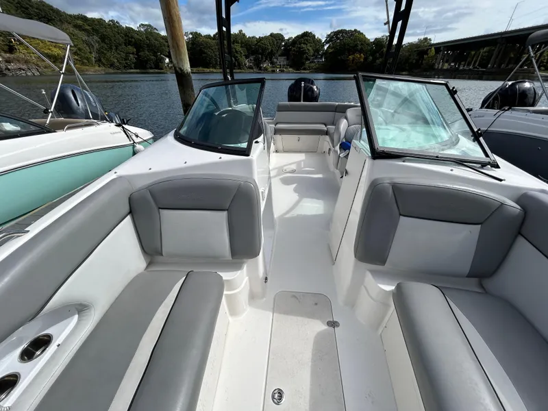Slide: The Image of 2021 NauticStar 243 DC boat interior with gray seating, docked on a calm lake. - 23