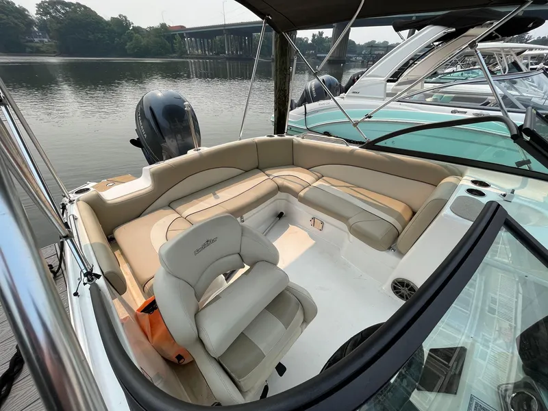 Slide: The Image of 2021 NauticStar 243 DC boat interior with beige seating, docked by a calm river. - 8