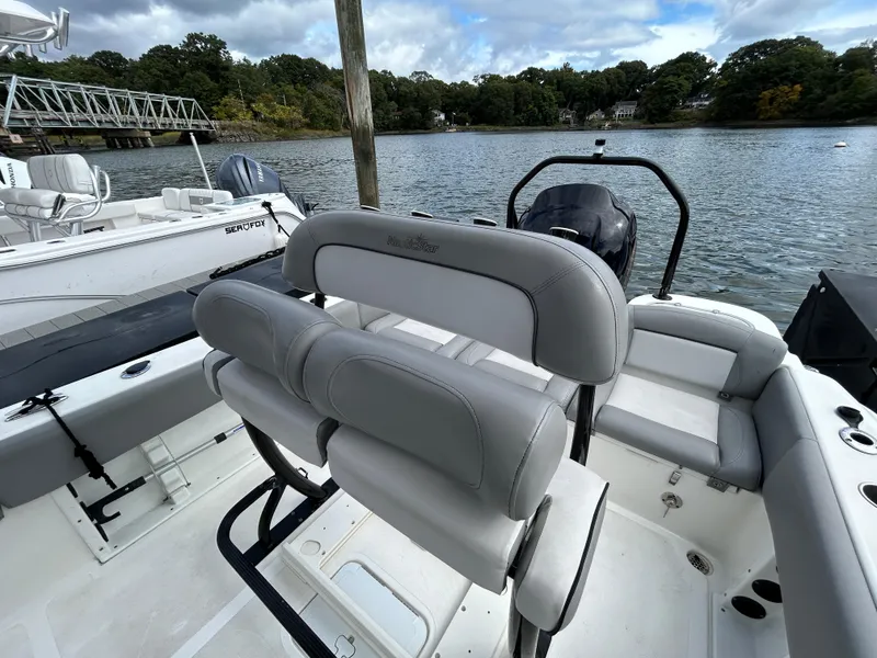 Slide: The Image of 2021 NauticStar 2302 Legacy boat interior with seating, docked on a scenic lake. - 13