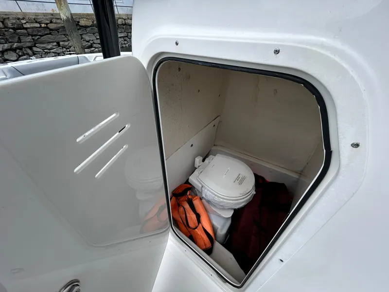 Slide: The Image of Storage compartment with portable toilet and life jacket on 2021 NauticStar 2302 Legacy boat. - 16