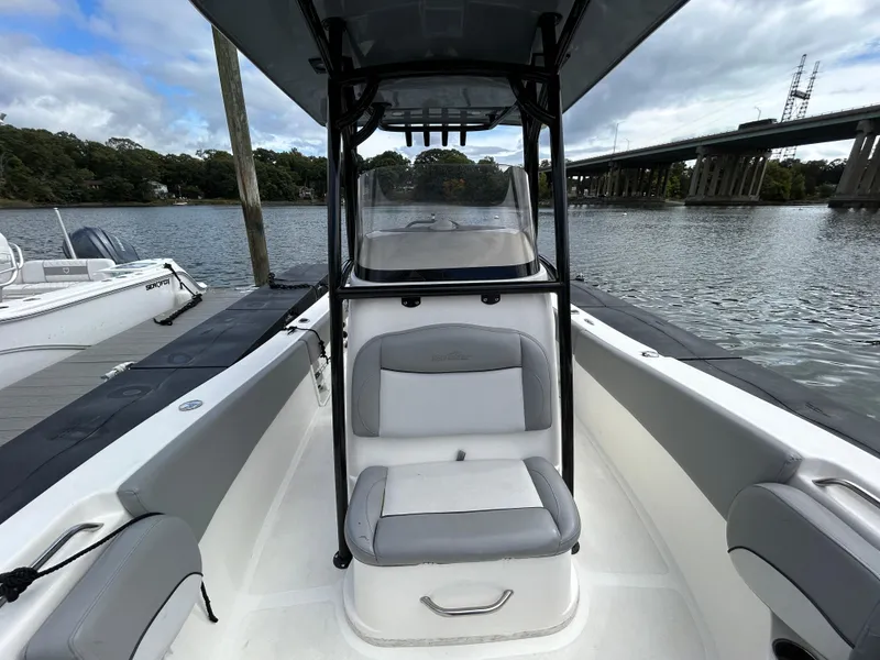 Slide: The Image of 2021 NauticStar 2302 Legacy boat interior with seating, docked by a river. - 17