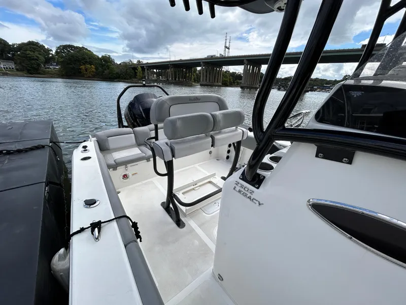 Slide: The Image of 2021 NauticStar 2302 Legacy boat interior, featuring seating and console, docked by a river. - 18