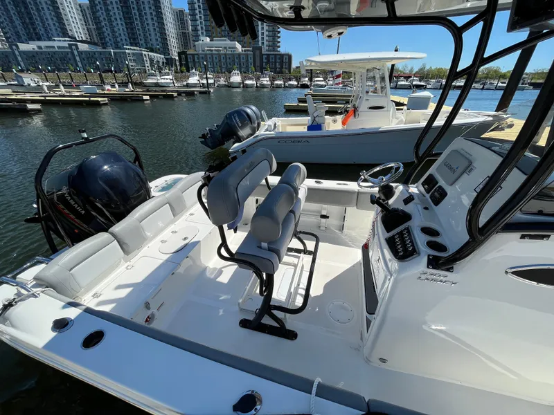 Slide: The Image of 2021 NauticStar 2302 Legacy boat docked at marina, featuring spacious seating and modern controls. - 21