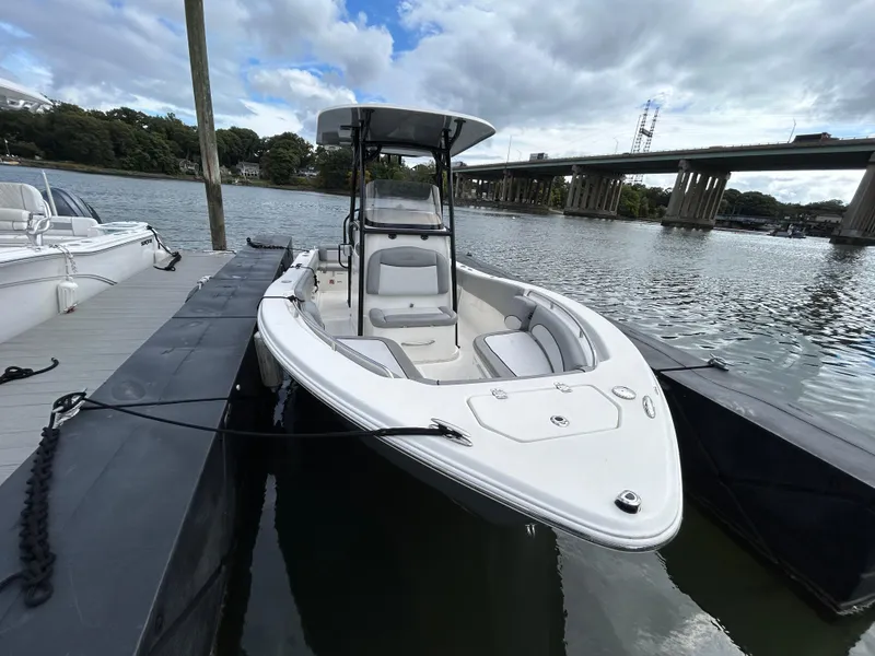 Slide: The Image of 2021 NauticStar 2302 Legacy boat docked by a river under a cloudy sky. - 4