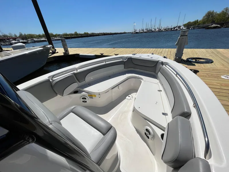 Slide: The Image of 2021 NauticStar 2302 Legacy boat interior with seating, docked by a serene waterfront. - 5