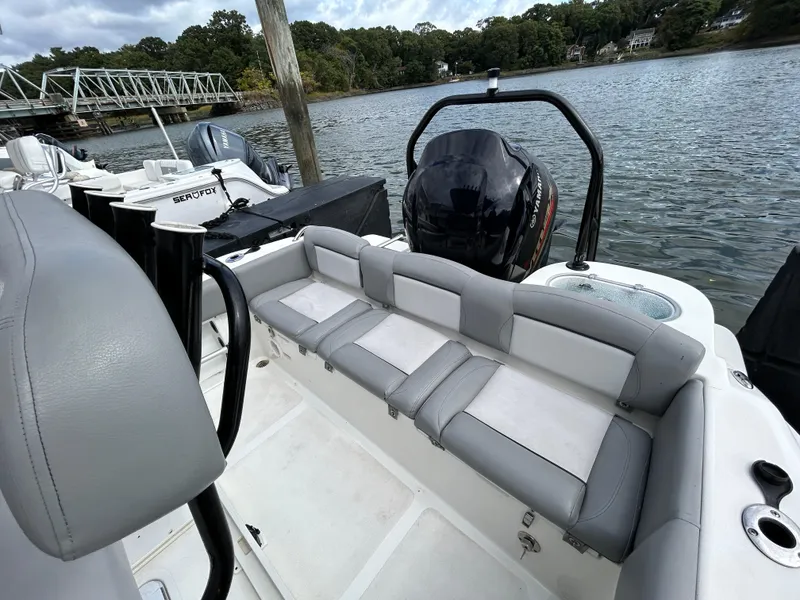 Slide: The Image of 2021 NauticStar 2302 Legacy boat with gray seating, docked by a serene lake. - 8