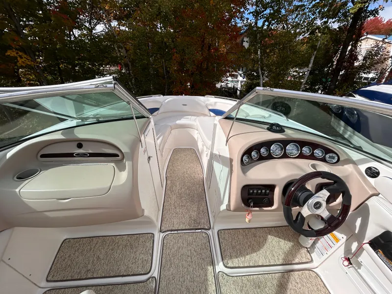 Slide: The Image of 2002 Chaparral 220 SSi boat interior with steering wheel and dashboard, surrounded by autumn foliage. - 45