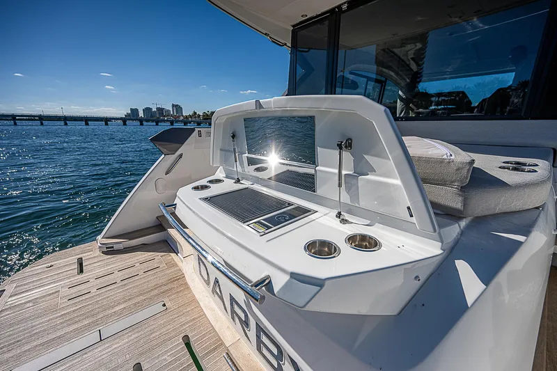 Slide: The Image of 2022 Beneteau Gran Turismo 45 yacht with outdoor kitchen, docked by scenic waterfront. - 18