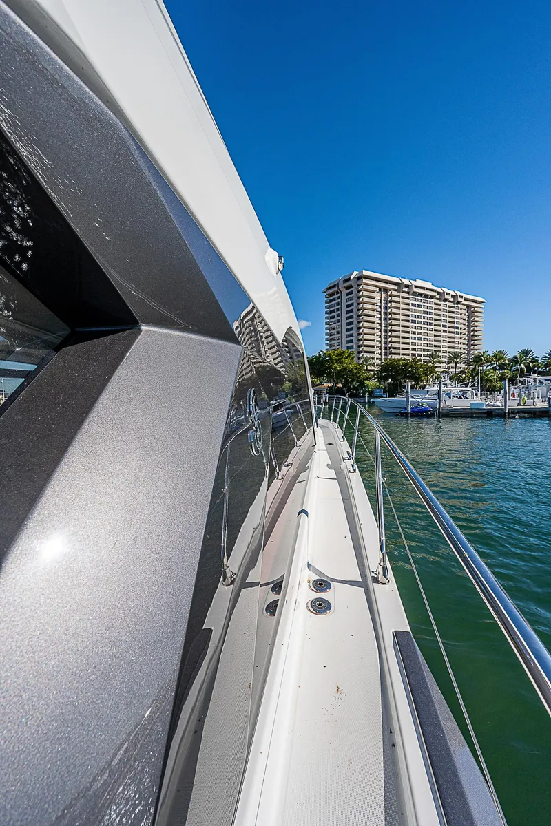 Slide: The Image of Beneteau Gran Turismo 45 yacht, 2022 model, cruising near a marina with a cityscape backdrop. - 22