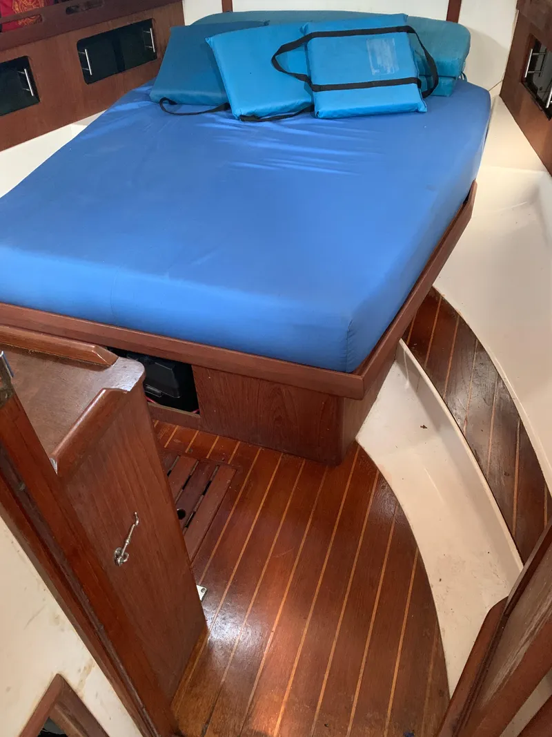 Slide: The Image of 1985 Hunter Legend 40 yacht cabin with blue bedding and wooden flooring. - 14