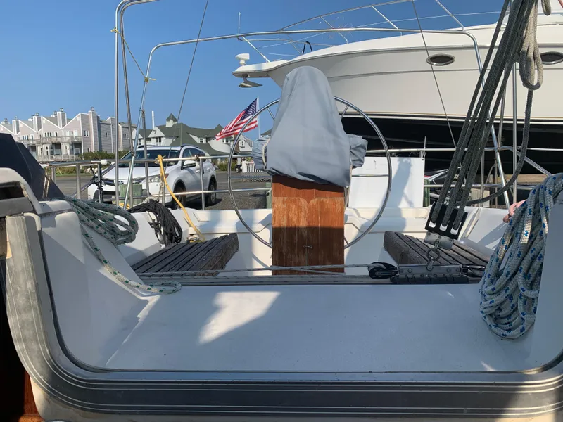Slide: The Image of 1985 Hunter Legend 40 sailboat cockpit with covered wheel, docked near waterfront homes. - 15
